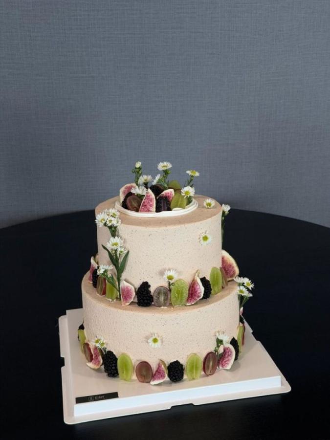 Two-tier cake ringed with macarons, berries and white blossoms