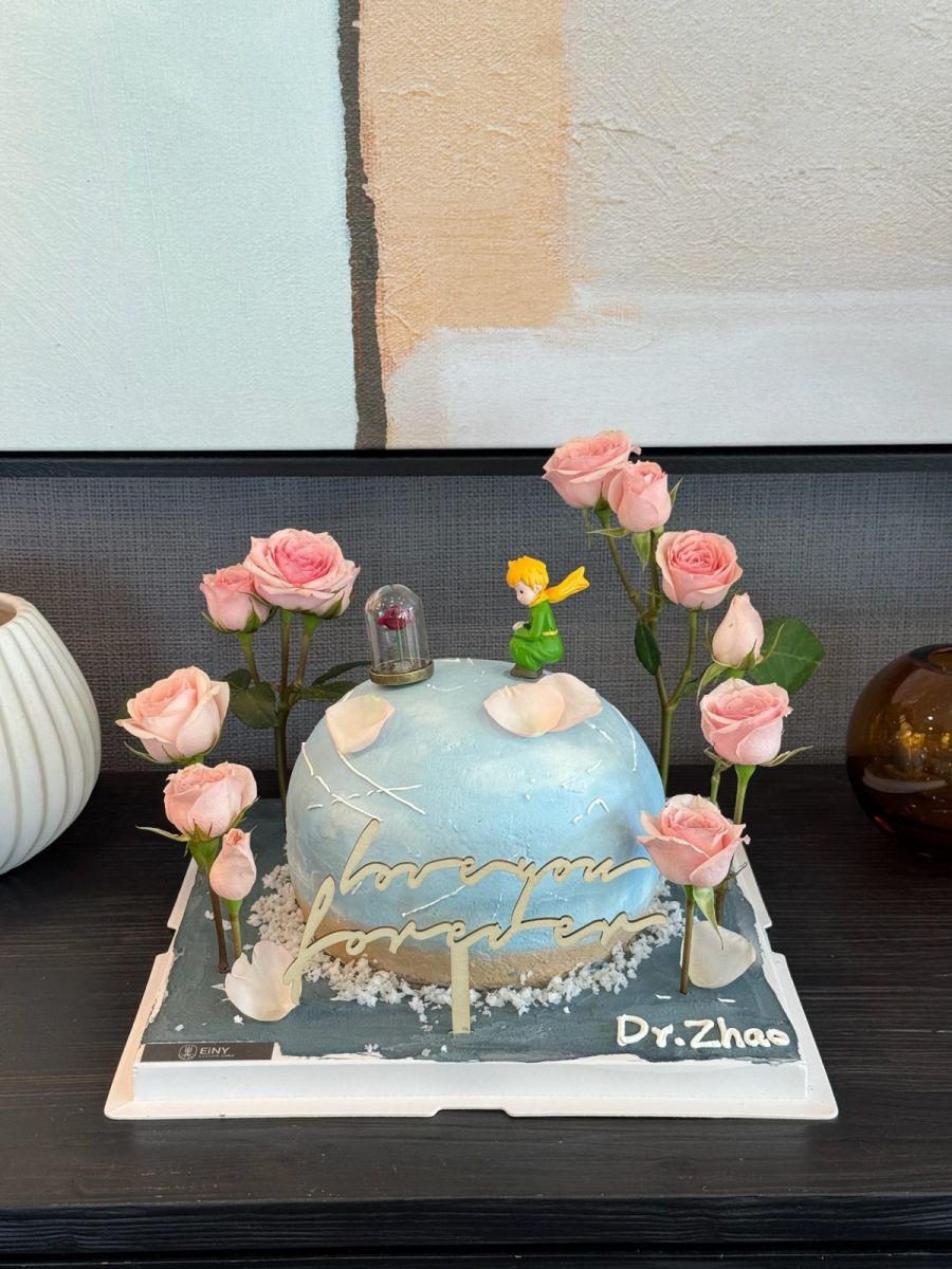 Pale blue planet cake with a tiny prince, a rose under glass and pink roses all around