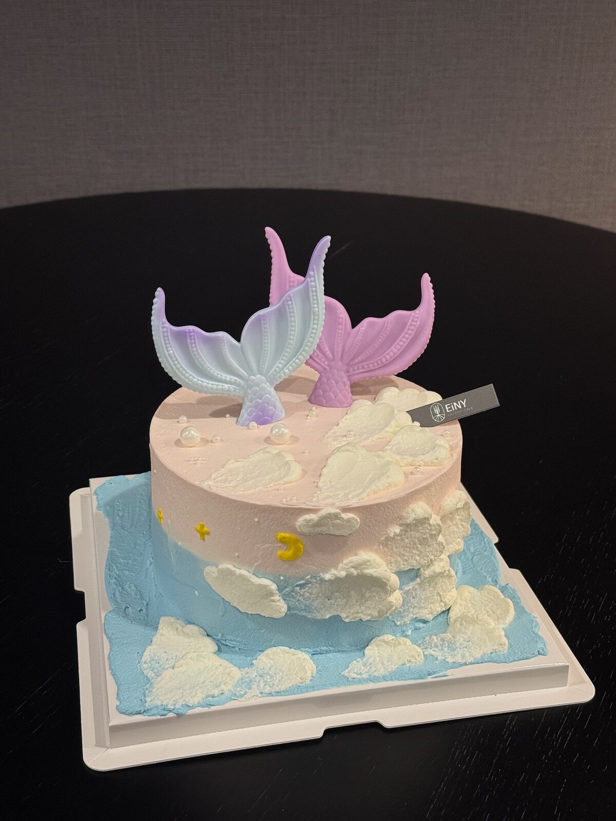 Cake with shimmering mermaid tails rising from piped cream waves