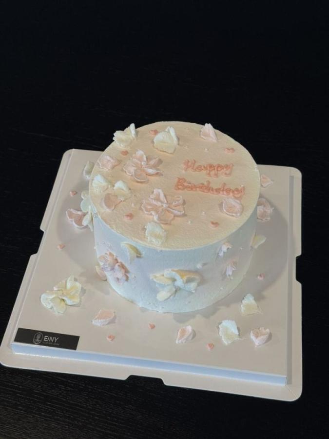 Pale cake with drifting pastel petals and a birthday message